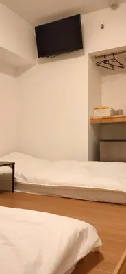 two beds in a room with a tv on the wall at Hostel Belle Via Tokyo in Tokyo