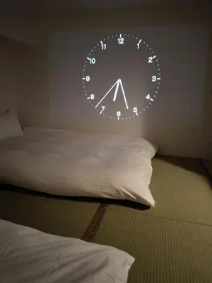 a clock hanging on a wall next to a bed at Hostel Belle Via Tokyo in Tokyo
