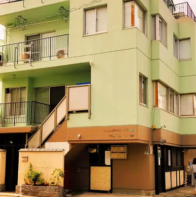 an apartment building with an open door and a balcony at Hostel Belle Via Tokyo in Tokyo