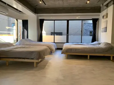 a room with three beds and a large window at Spacious studio(62m2) in western Shinjuku in Tokyo