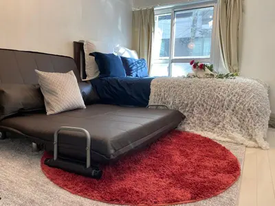a couch in a living room with a red rug at BEST LOCATED SHINJUKU CENTRAL Full-Furnished APARTMENT 3minWalk to Station1 in Tokyo