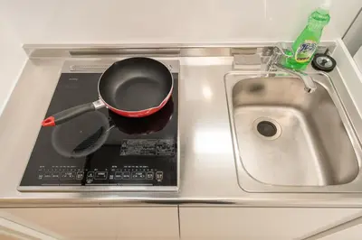 a kitchen counter with a frying pan and a sink at Real Okubo Apartment Hotel in Tokyo