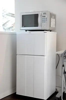a microwave sitting on top of a white refrigerator at \u30b2\u30b9\u30c8\u30cf\u30a6\u30b9\u6634 in Tokyo