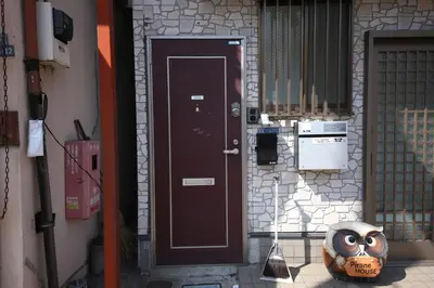 a brown door with a owl mask next to it at Pirane House 201 \u6771\u4eac\u30b9\u30ab\u30a4\u30c4\u30ea\u30fc\u6d45\u8349 \u62bc\u4e0a\u99c5\u304c\u5f92\u6b69\u570f\u5185 \u7121\u6599wifi in Tokyo