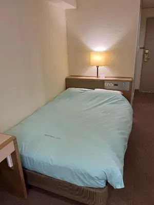 a large bed in a hotel room with a lamp at Olympic Inn Kanda in Tokyo