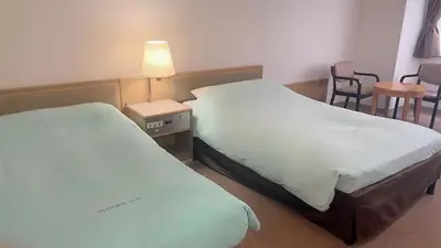 a hotel room with two beds and a table and chairs at Olympic Inn Kanda in Tokyo