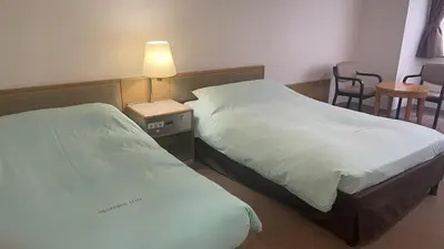 a hotel room with two beds and a table and chairs at Olympic Inn Kanda in Tokyo