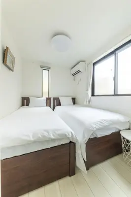 two beds in a bedroom with white walls and a window at SKYTREE HOUSE in Tokyo
