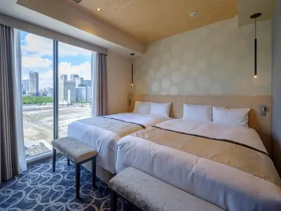 two beds in a hotel room with a large window at Tosei Hotel Cocone Tsukiji Ginza Premier in Tokyo