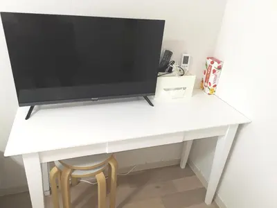 a television sitting on a white desk with a stool at B Shinjuku Self Check in in Tokyo
