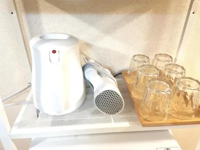 a white juicer sitting on a shelf with glasses at B Shinjuku Self Check in in Tokyo