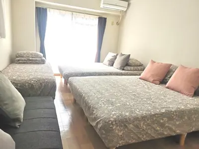 a room with three beds in front of a window at B Shinjuku Self Check in in Tokyo