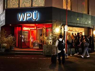 a group of people walking outside of a store at night at WPÜ HOTEL Shinjuku in Tokyo