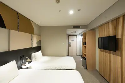 a hotel room with two beds and a flat screen tv at WPÜ HOTEL Shinjuku in Tokyo