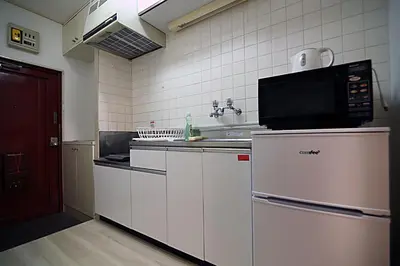 a kitchen with white cabinets and a microwave at HEISIEI HOUSE Shin-Ōkubo FREE WIFI in Tokyo