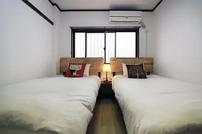 two twin beds in a room with a window at HEISIEI HOUSE Shin-Ōkubo FREE WIFI in Tokyo