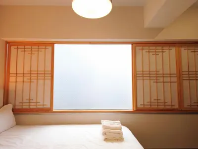 a bedroom with a large window with towels on a bed at Ueno Colon Hotel in Tokyo