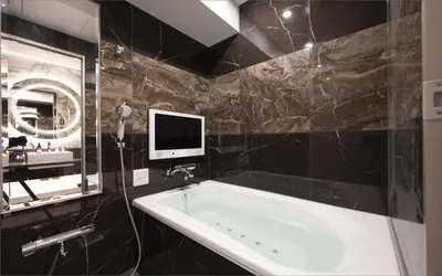 a bathroom with a tub and a tv on the wall at HOTEL KABUKI in Tokyo