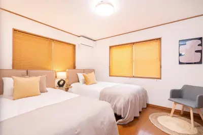 a bedroom with two beds and a chair in it at Hanamikaku\u522b\u5885110\u5e73\u65b9 4LDK,\u4e1c\u4eac\u7ad913\u5206 \u65b0\u5bbf25\u5206 \u79cb\u8449\u539f14\u5206 \u9280\u5ea730\u5206 \u6e0b\u8c3736 in Tokyo
