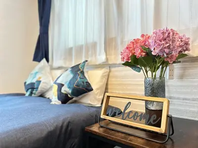 a mirror on a table next to a bed with flowers at nestay apartment tokyo shinjuku in Tokyo