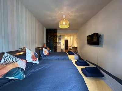 a bedroom with two beds with blue sheets and a tv at nestay apartment tokyo shinjuku in Tokyo