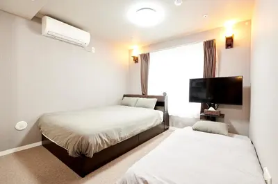 a bedroom with two beds and a flat screen tv at \u65b0\u898f\u30aa\u30fc\u30d7\u30f3\u30fb\u65b0\u5bbf\u99c52\u30ad\u30ed\u570f\u5185\u30fb\u7bc93\u5e74\u30c7\u30b6\u30a4\u30ca\u30fc\u30ba\u30de\u30f3\u30b7\u30e7\u30f3 in Tokyo