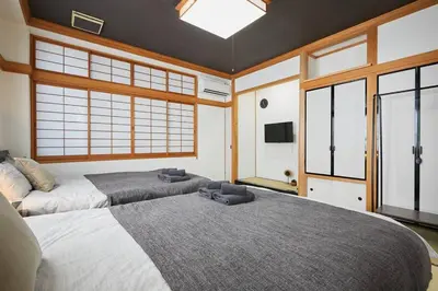 a bedroom with two beds and a large window at Japanese Tradition Hotel Evergreen in Tokyo