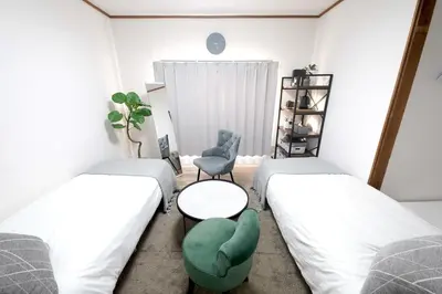 two beds in a room with a table and a chair at Close to Shinjuku!Twin beds,Projector,Appliances! in Tokyo