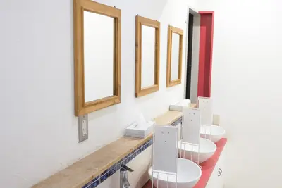 a row of three toilets in a bathroom with windows at Hostel Lodging Tokyo Ueno in Tokyo