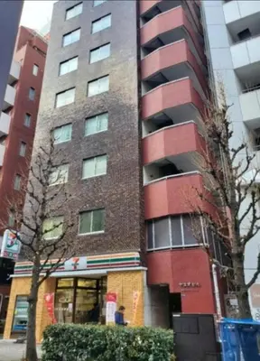 a tall red brick building with a man standing in front of it at \u6b4c\u821e\u4f0e\u753a704 in Tokyo