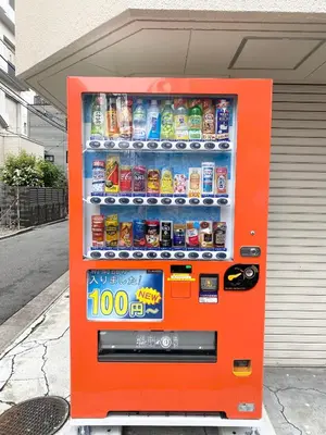 an orange soda vending machine on the street at Ueno\u6b63\u548c\u30d3\u30eb in Tokyo