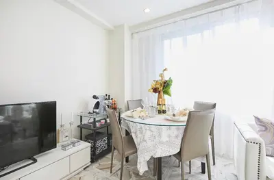 a dining room with a table with chairs and a television at Reimi Mondo9 in Tokyo