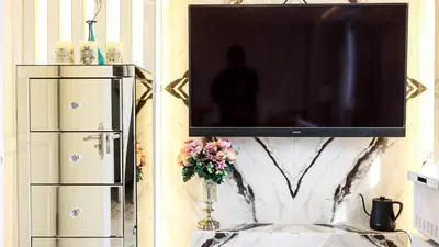a television on a wall with a vase of flowers on a table at Reimi Mondo9 in Tokyo
