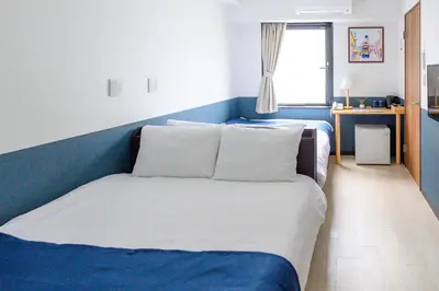 a blue and white bedroom with a bed with pillows at Ueno Woo Hotel in Tokyo