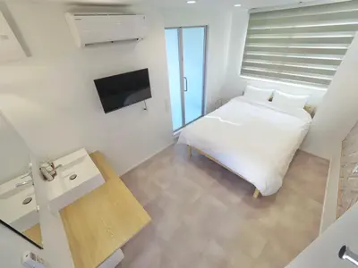 a white bedroom with a bed and a television at Hotel Apreton in Tokyo
