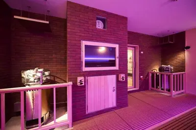 a room with a brick wall with a flat screen tv at Sauna & Cabin Thermae-yu Nishiazabu in Tokyo
